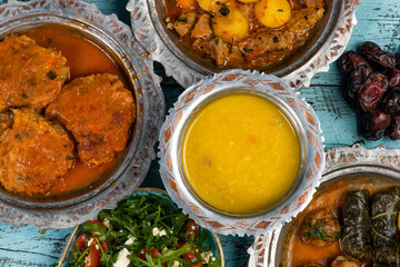 Eid Mubarak Traditional Ramadan Iftar dinner. Assorted tasty food in authentic rustic dishes on wooden blue background. Turkish Bosnian food meat kebab, pita, Sarma, klepe, sogan dolma.