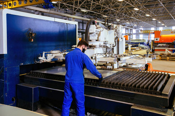 Worker puts steel sheet into loading unit of cutting machine.