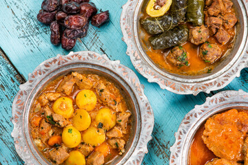 Eid Mubarak Traditional Ramadan Iftar dinner. Assorted tasty food in authentic rustic dishes on wooden blue background. Turkish Bosnian food meat kebab, pita, Sarma, klepe, sogan dolma.