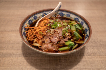 Chinese Spicy goulash Beef Noodle Soup on wooden counter table. 