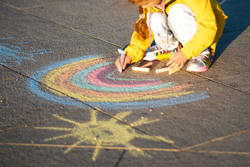 A girl draws a rainbow in the rays of the sunset.