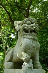 Foto auf Acrylglas Historisches Monument Vertical shot of Japanese stone lion statue in the park with green trees in the background
