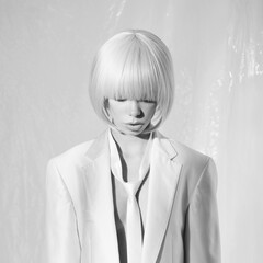 Studio fashion photo of young elegant woman in white men's jacke