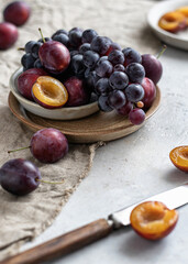 Ripe grapes and plums on linen tablecloth, selective focus. Autumn mood still life composition