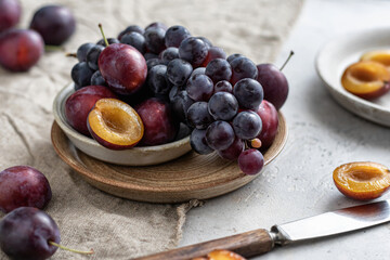 Ripe grapes and plums on linen tablecloth, selective focus. Autumn mood still life composition