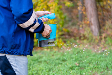 Garden worker in the residential backyard with fertilizing lawn.
