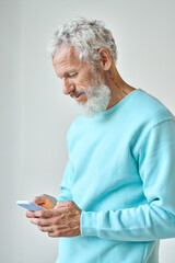 Older senior bearded stylish hipster man holding cell phone looking at cellphone using smartphone...