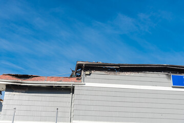 Close up red shingle roof and façade exterior siding with fire damaged of motel in midtown...