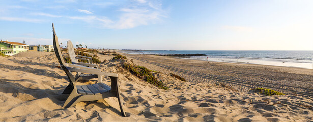 Panoramic view of beach chairs in profile on an expansive sandy beach