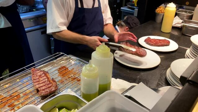 Chef Plating Grilled Steak In A Professional Restaurant Kitchen