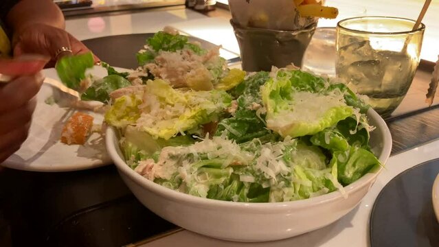 Close Up of African American Woman Plating Up Caesar Salad At A Restaurant