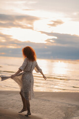 girl at sunset dancing on the beach. flying dress