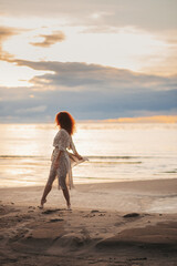 girl at sunset dancing on the beach. flying dress