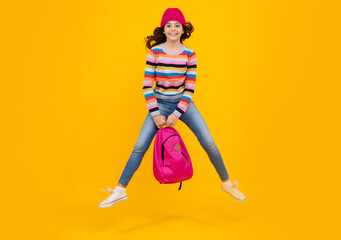 Winter school. Teenager school girl with backpack in autumn clothes on yellow isolated studio background. Crazy jump and run, jumping kids.