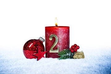 second sunday of advent red candle with golden metal number two red decoration one on  snow isolated background