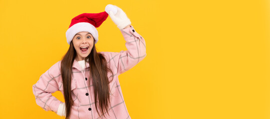 Winter girl. amazed child in santa claus hat and winter mittens on yellow background. Banner of christmas child girl, studio kid winter portrait with copy space.
