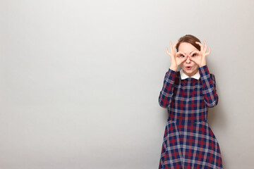 Portrait of surprised young woman showing okay gestures near eyes