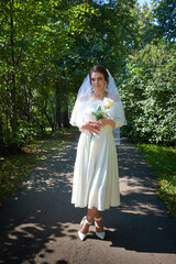 Young beautiful European woman in a white wedding dress and a veil and yellow rose in the park. Summer, celebration, fashion, beauty, girl. Fashion bride, meeting, holiday