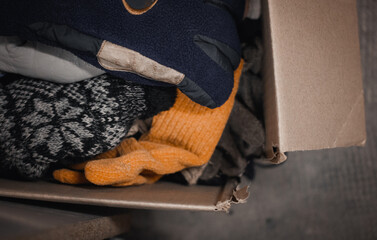 Cardboard box filled with different warm clothes, second hand, used clothing accessories for poor....