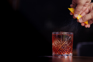 Man's hands pouring negroni into the glass from a pitcher. Bar from a bar. - obrazy, fototapety, plakaty