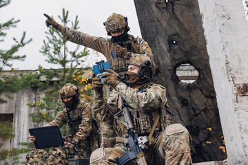 Modern army soldiers using aerial drone for artillery guidance and scouting view enemy positions in...