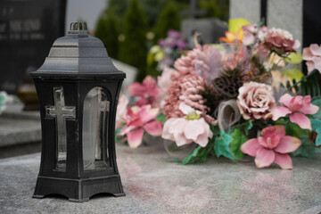 Candle and beautiful artificial bouquet on the grave.