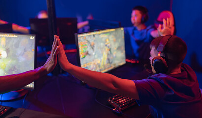 Professional gamer man greeting team fists hands online game in neon color blur background. Soft focus, back view © Parilov