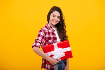 Teenager child in shirt holding gift box on yellow isolated background. Gift for kids birthday. Happy teenager, positive and smiling emotions of teen girl.