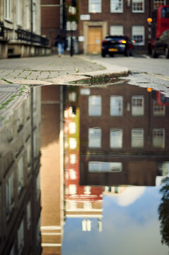 Blurred image of London street and buildings in reflection of puddle of water