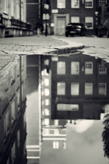 Blurred black and white monochrome image of London street and buildings in reflection of puddle of water
