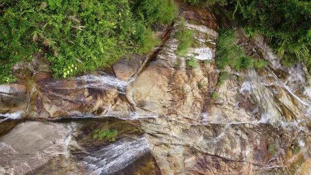 Aerial rotating look down water at rocky waterfall in Malaysia