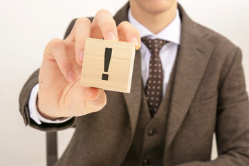 businessman holding wooden block with the exclamation point