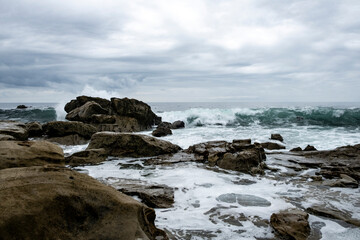 Crashing waves wearing boulders smooth on the shore of Laguna Beach, California.
