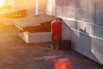 Red gas cylinder near the building in the sun. Gas cylinder near the wall of the building.