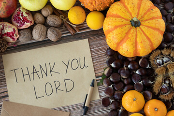 Thank You, LORD, handwriting on an old vintage paper with pen and various autumn fruit on wooden...