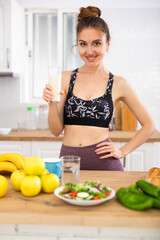 Obraz na płótnie Canvas Happy slim sporty girl drinking yogurt in home kitchen