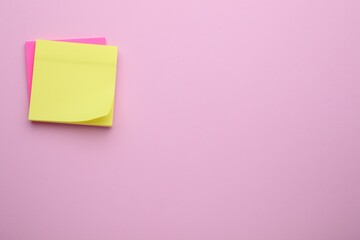 Paper notes on pale pink background, top view. Space for text