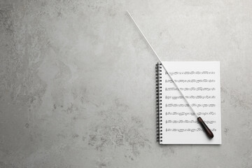 Conductor's baton and sheet music book on grey background, top view. Space for text