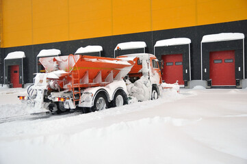 Cleaning the territory of a modern warehouse complex from snow accumulations with specialized road...