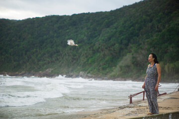 elderly woman enjoying trip, tree  and sea in the background, on a park smile pigeon fly