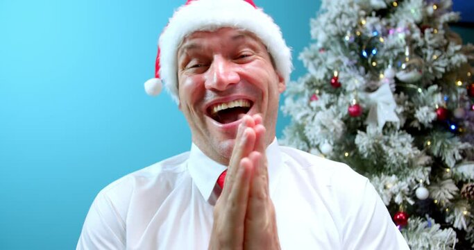 Happy smiling dad in christmas hat santa claus receiving a gift, looking at the camera, rubbing his hands in happiness. Happy man in delight with surprise or news