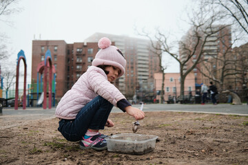 Girl digging in the dirt on the playground on a foggy fall day