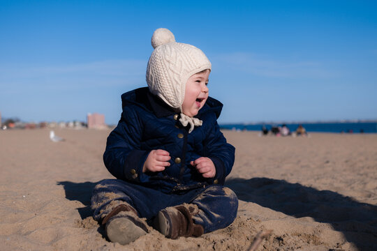 Extatic young boy is playing in the sand during in cold weather