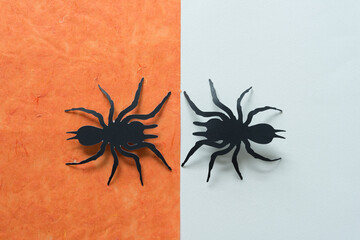 two paper spider shapes on orange and white paper background
