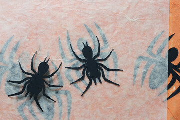 stylized paper glyph or dingbat cutouts of spiders on tissue paper with spider silhouettes beneath