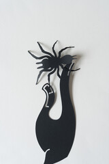 3d stylized paper glyph or dingbat cutout in the shape of a spider with paper hand silhouette