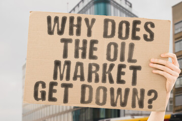 The question " Why does the oil market get down? " is on a banner in men's hands with blurred background. Depressed. Drop. Fossil. Fuel. Oil. Petroleum. Petrol. Rating. Crude. Energy. Market