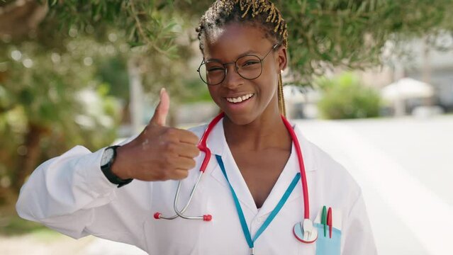 African american woman doctor smiling confident doing ok gesture with thumbs up at park