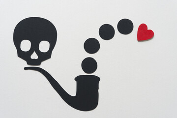 black paper skull head, pipe, circles, and a wooden heart painted red on blank paper