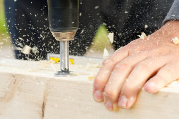 Carpenter drilling holes in the wood beam. wooden frame domestic house building. drilling a hole with a handheld drill